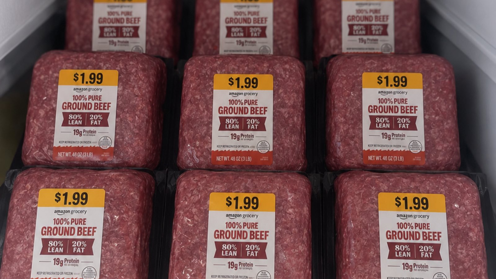 Packages of Amazon Grocery 80% lean ground beef in a refrigerated case, each with a yellow $1.99 price sticker.